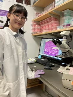 Young woman standing next to microscope.